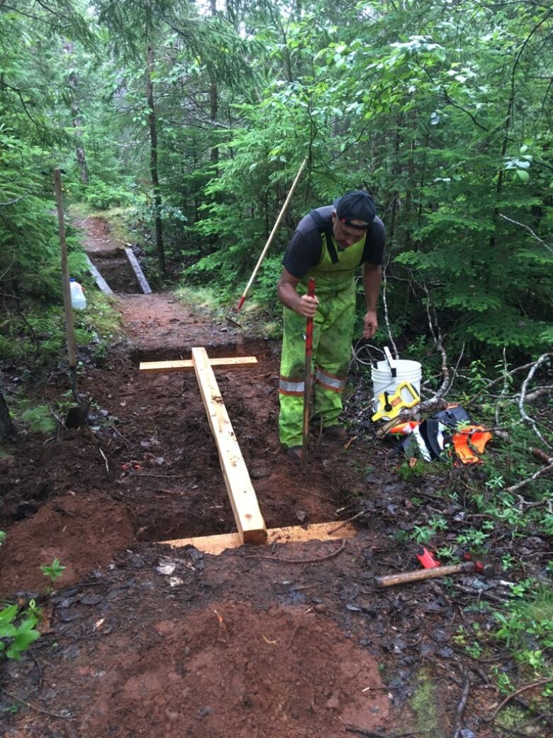 man in the woods working on trail 