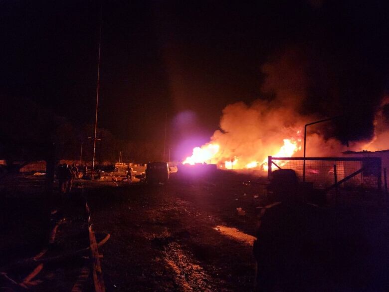 A fire is shown at an industrial area in a nighttime photo.