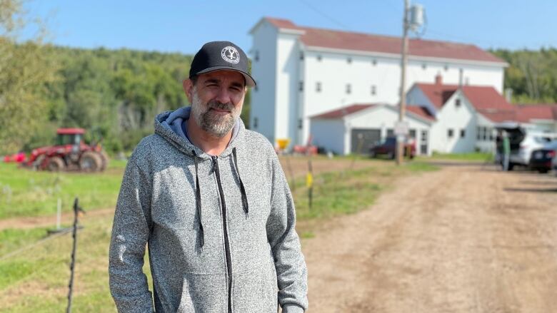 Charlie Burrell stands in front of large white farm building