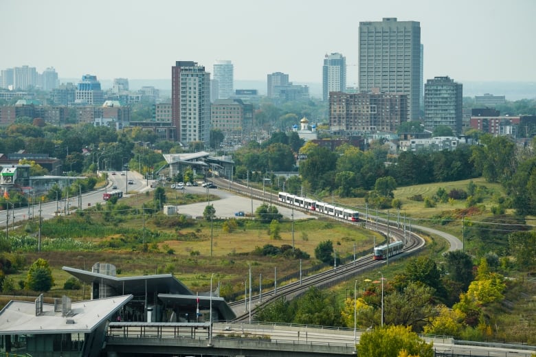 A light rail train line runs between two above-ground stations on the edge of a city centre in late autumn.