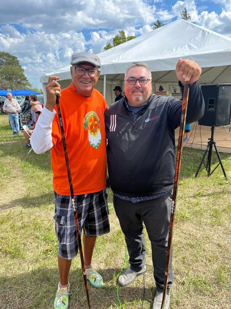 Eugene Arcand (left) and Clay DeBray (right) stand with their specialized Every Child Matters hockey sticks. 