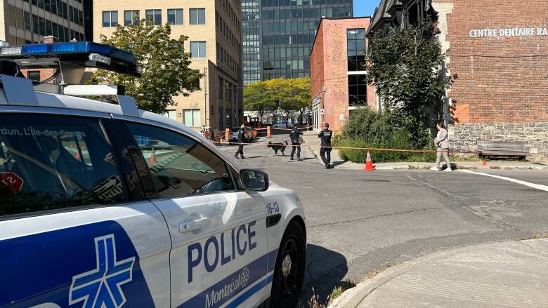 A police cruiser parked near a taped off scene.