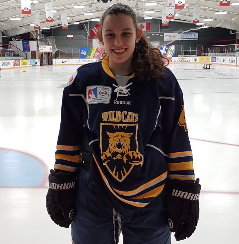 A female hockey player on the ice at a rink.