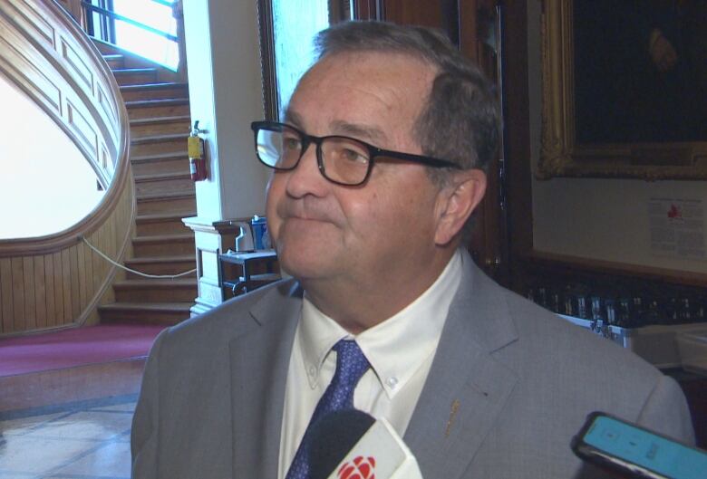 A man in a suit with a CBC-branded mic being pointed at him