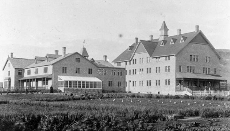 An archival photo of a four-to-five storey stone building complex, with porches.