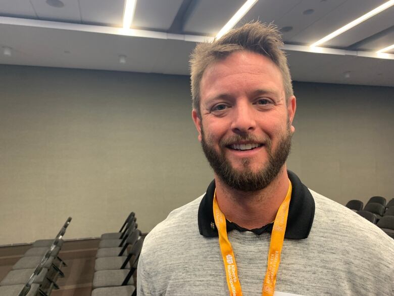 A man wears a grey shirt and yellow lanyard.