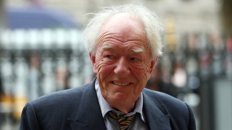  A man in a blue jacket and yellow tie smiles.