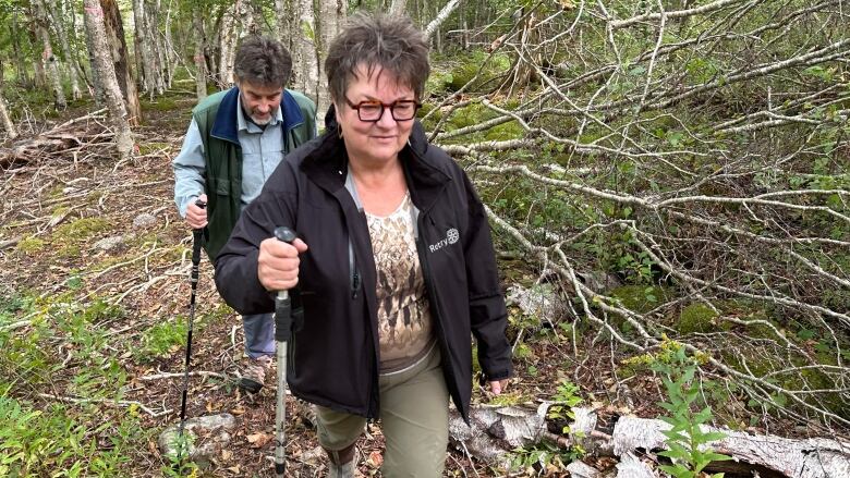 Two people are shown hiking through the woods.