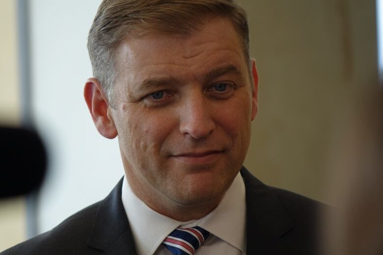 A man with a suit and tie smiles. 