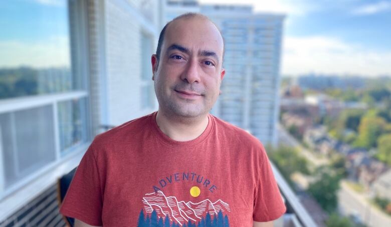 A man poses for a photo on his balcony. 