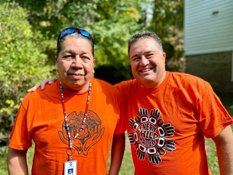 Two men in orange every child matters shirts