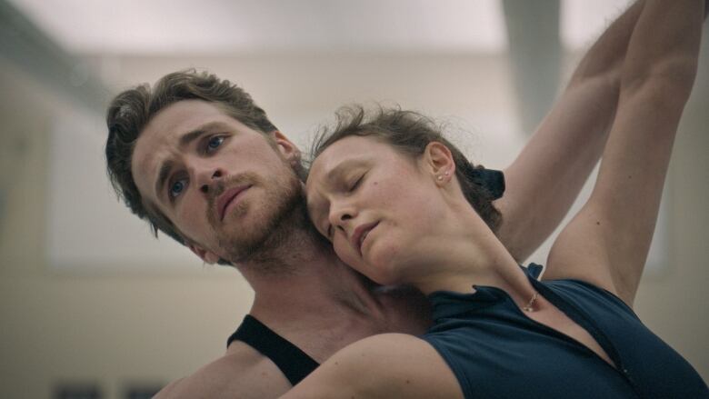 A man and a woman lean against one another mid-dance. 