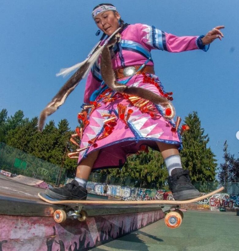 A woman in a jingle dress on a skateboard