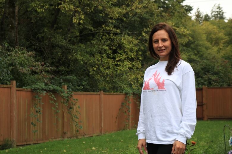 Desiree Belisle stands near a garden she planted at the recovery home site. She says over the years she's run into barriers accessing a recovery home, including extended wait lists.