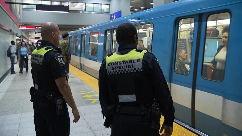 Two men stand in a metro tunnel.