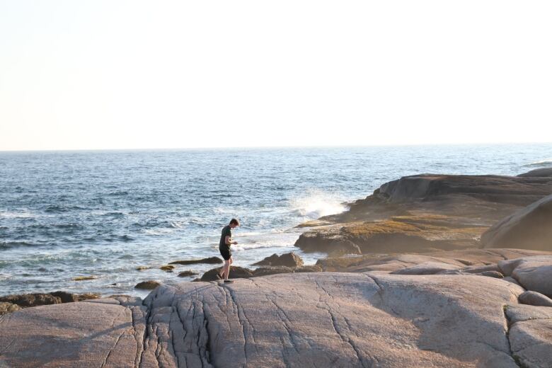 A man seen walking on giant rocks at the shoreline