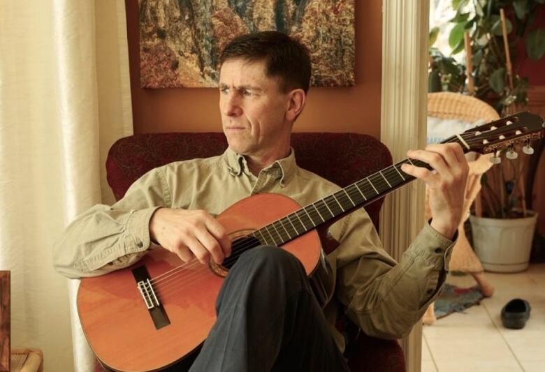 A man plays guitar in his living room