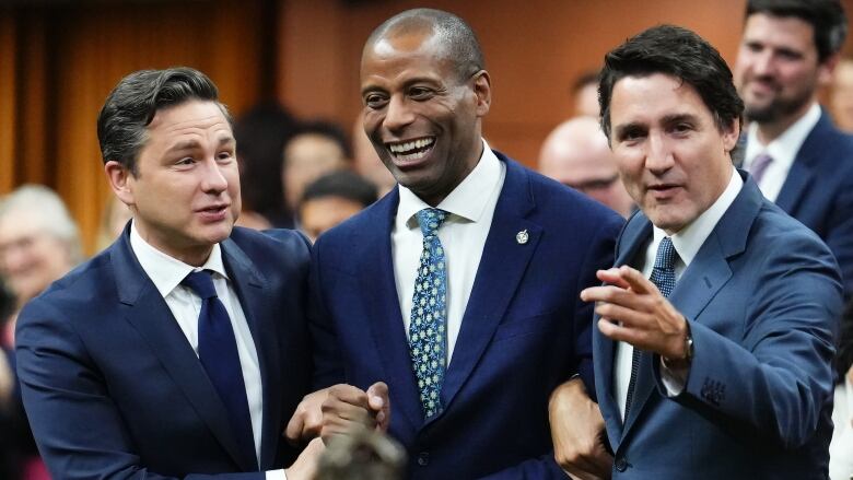 Three men walk arm-in-arm in a government building