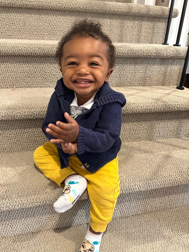 Baby sits on carpet on a staircase.