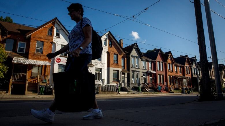 A person walks by a row of houses in Toronto.