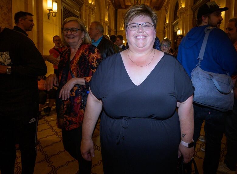 A woman wearing a black dress stands for a photo. 