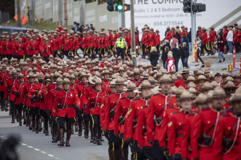 Hundreds of Mounties march along a highway.