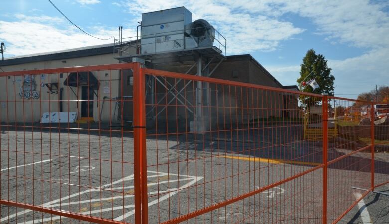 orange construction fencing surrounds a hockey arena 