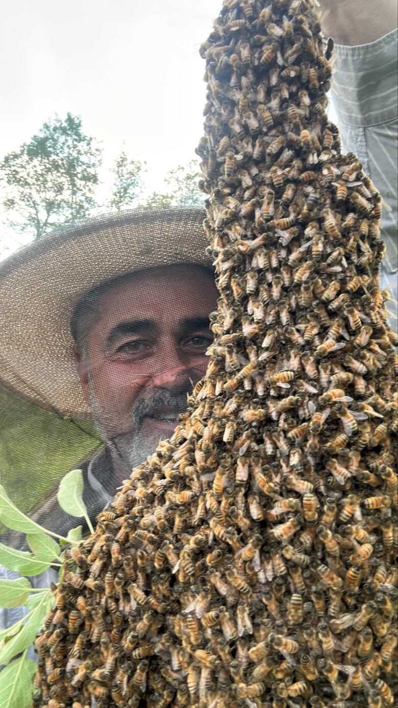 Man next to elongated beehive