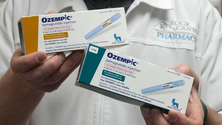 A pharmacist holds two boxes of Ozempic.