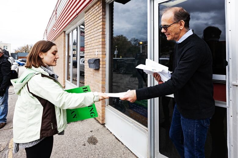 A federal MP staffer accepts a letter from an advocate outside the office of Dan Vandal.