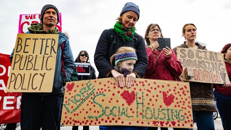 A mother and daughter hold signs at the rally outside the office of MP Dan Vandal.