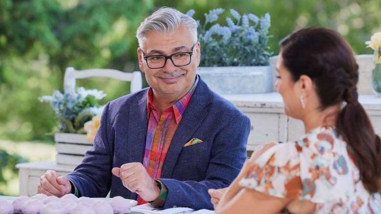 Bruno is setting at a table and smiling at Kyla who has her back to the camera.