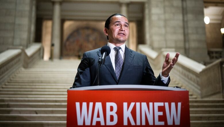 A politician addresses media inside a legislative building.