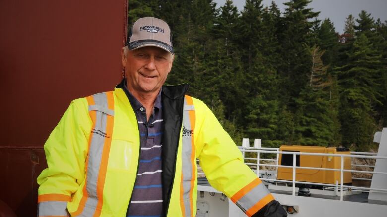 A man in hi viz gear stands on the deck of a ferry