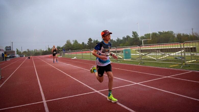 A young runner approached the finished line of the race with another runner behind him.