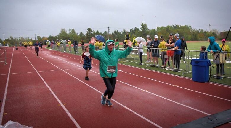 A younger races their hands as they approach the finish line. 