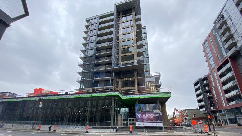 A condo building under construction sits at the corner of a city intersection 