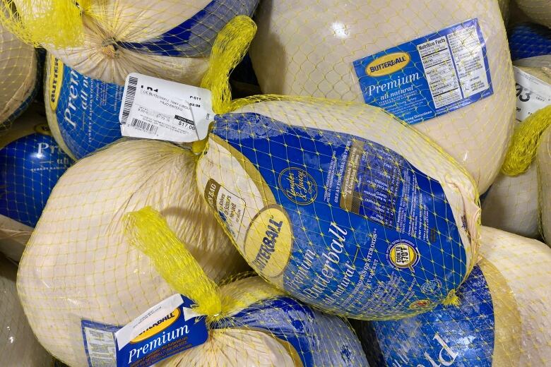 Several frozen turkeys being sold at a grocery store. 