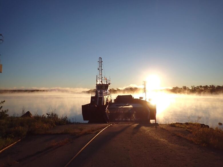 A ferry leaves the dock on a misty morning in golden sunlight