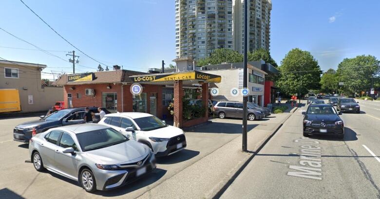 Two women crossing the street outside a mixed-use commercial and residential building.