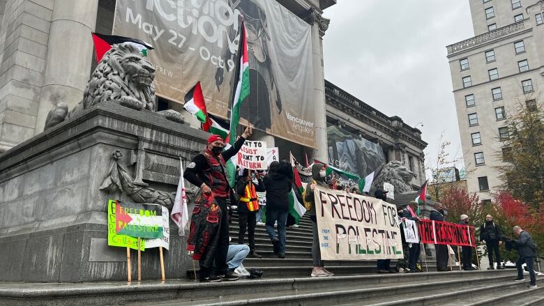 Protesters in front of an art gallery hold up a banner that reads 'Freedom for Palestine'.