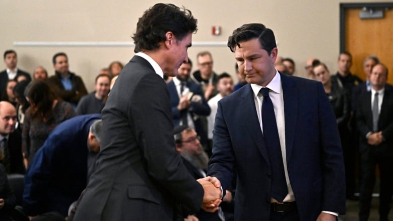 Two politicians shake hands at an event.