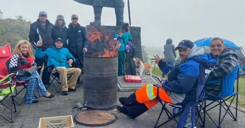 A group of people sitting in camping chairs around a barrel fire on Confederation Hill.