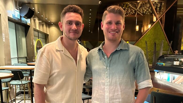 Two young men standing in a restaurant. 