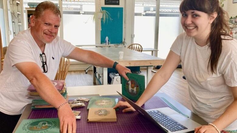 Two people stand at a desk 