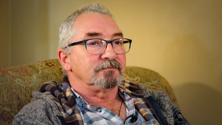 A man wearing glasses gazes past the camera.