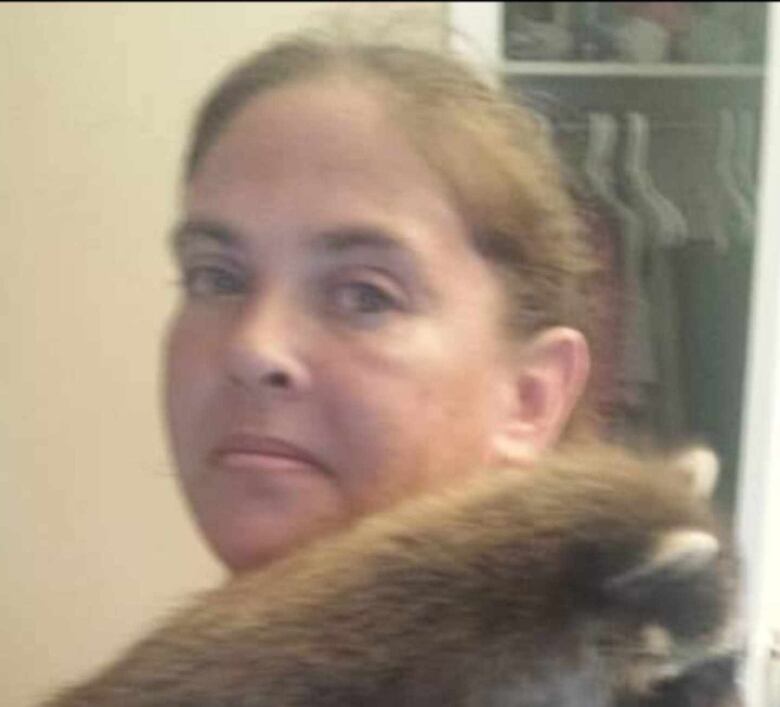 Kari Lynn Rose Campbell holds a raccoon cub.