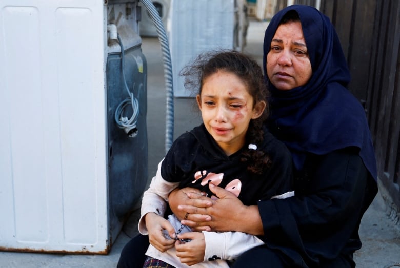 A young girl, crying, sitting on an older woman's lap