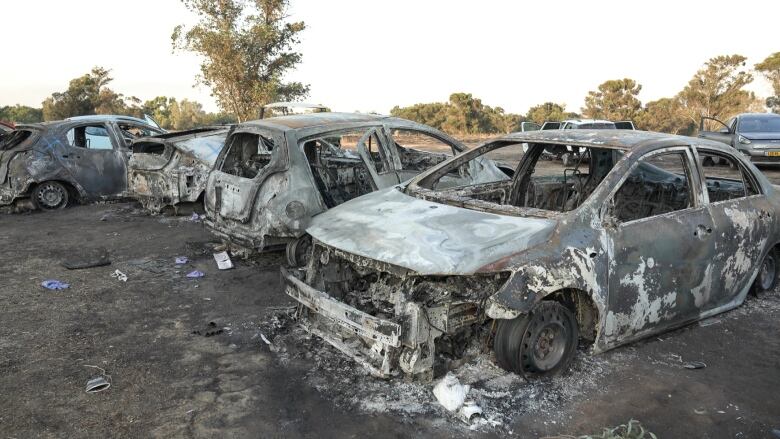 Burned-out cars are seen in a field.