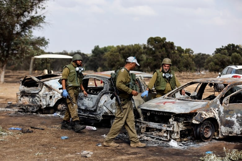 Soldiers walk around burnt cars.